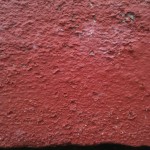 Close-up of surface of red painted brick, showing slight signs of aging