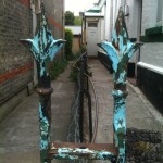 Corroden blue-green railing tops frame a long alleyway.