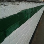 A green stripe on a white wall with a black top, shown in perspective so that the wall narrows in the distance.