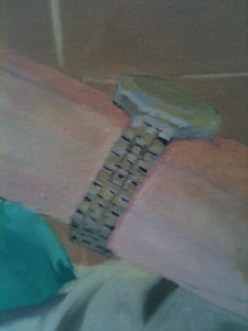 Close-up of watch, with strap painted in tiny patches of grey and yellow, and with heavily incised shadows