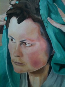Close-up of artist's face framed by green cloth held in place by hands.