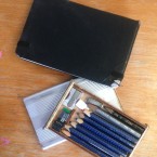 A sketch book and pencil case.  The pencil case is a tray inside an aluminium sleeve.